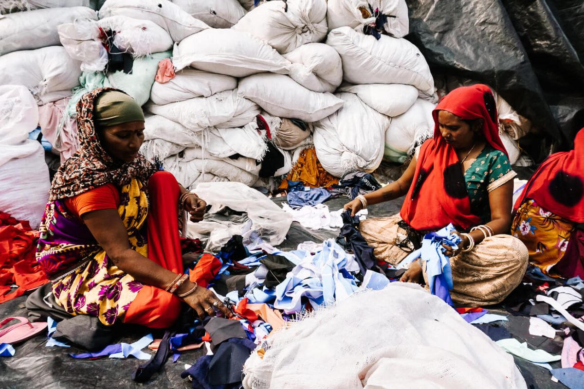 In de kleding recycling straat in Sanjay Colony zijn verschillende kleine bedrijfjes gevestigd, die elk verantwoordelijk zijn voor grote stapels gedragen kleding.