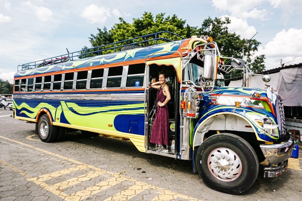 Vrouw voor typische bus in Guatemala 