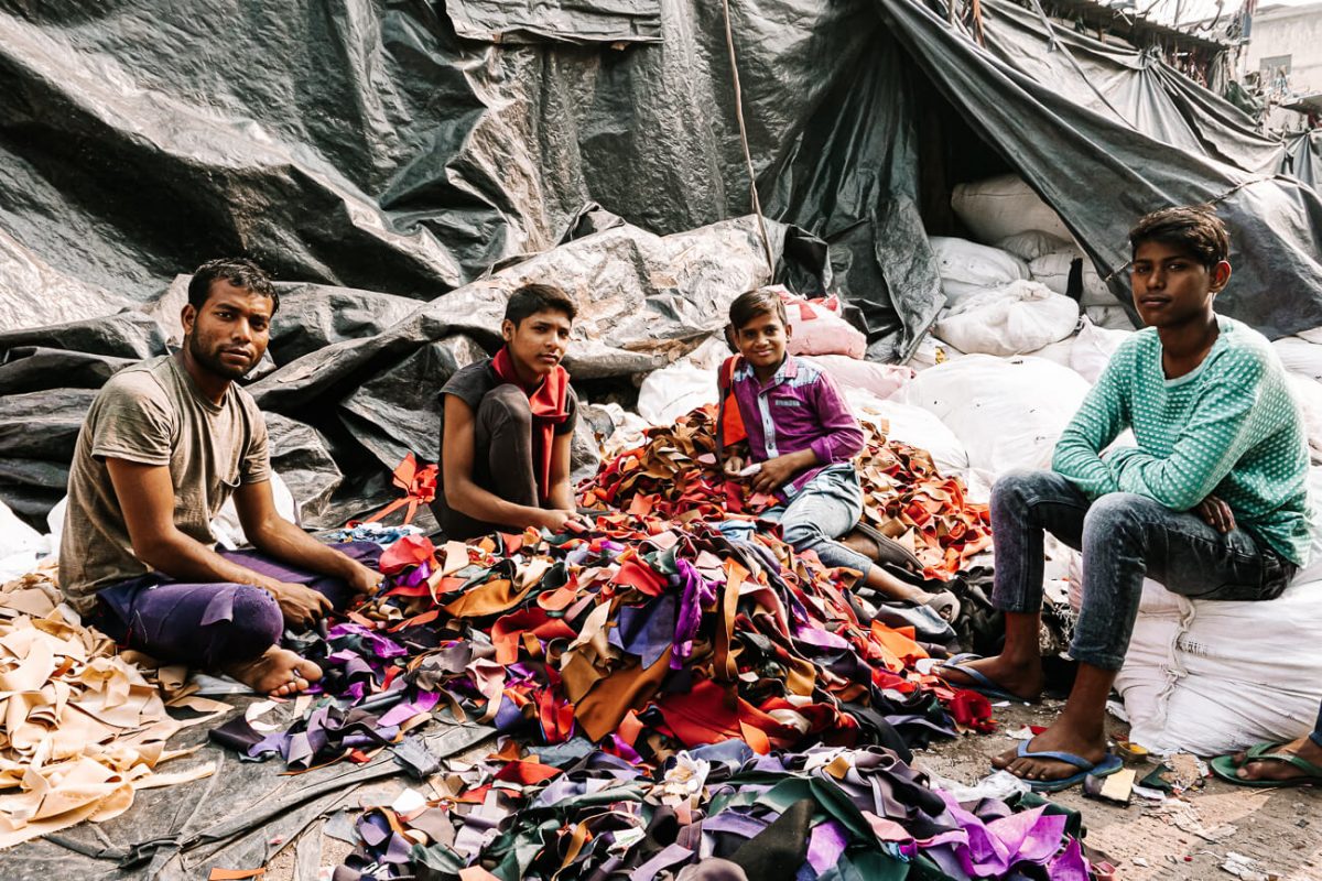 In de kleding recycling straat in Sanjay Colony zijn verschillende kleine bedrijfjes gevestigd, die elk verantwoordelijk zijn voor grote stapels gedragen kleding.